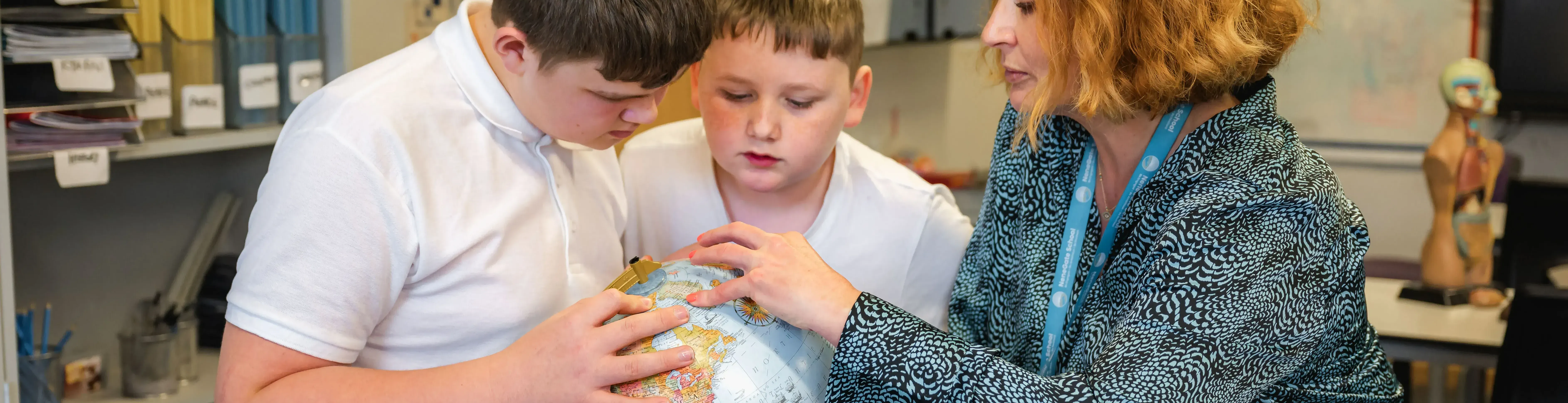 Students and teacher with globe in Geography