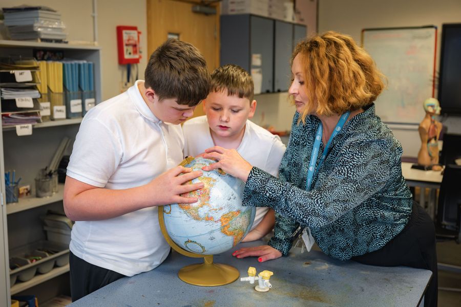 Students and teacher looking at a Globe in Geography